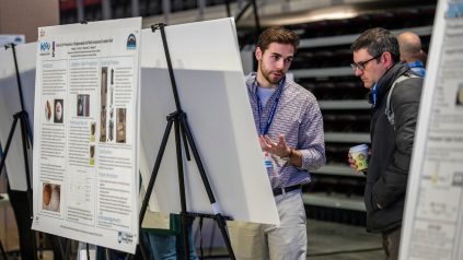 A student discusses his research with an attendee of UMSS