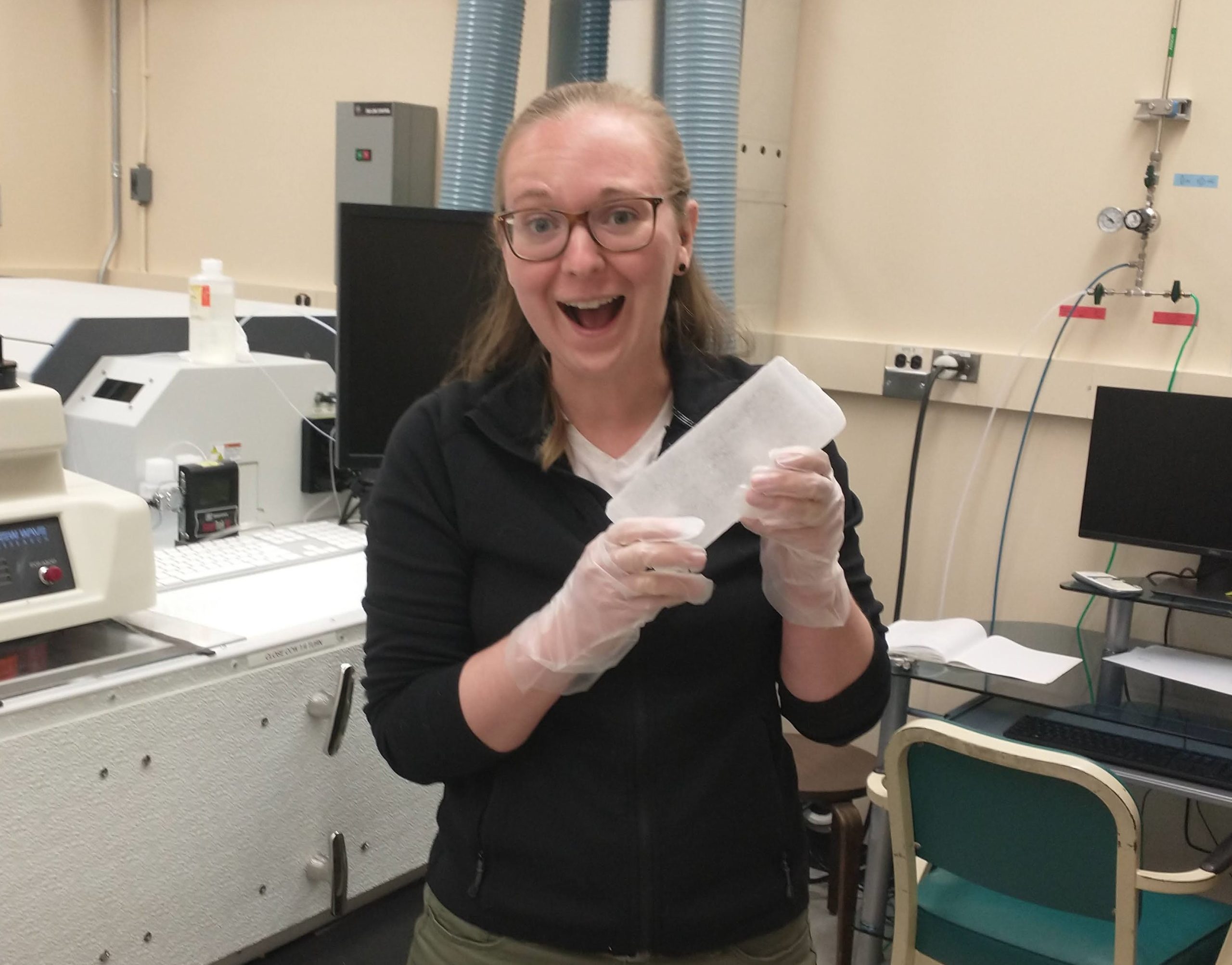 Hanna Brooks posing in a laboratory, holding up a container of samples.