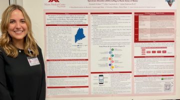 Ellie Walker poses beside her poster at the UMaine Student Symposium