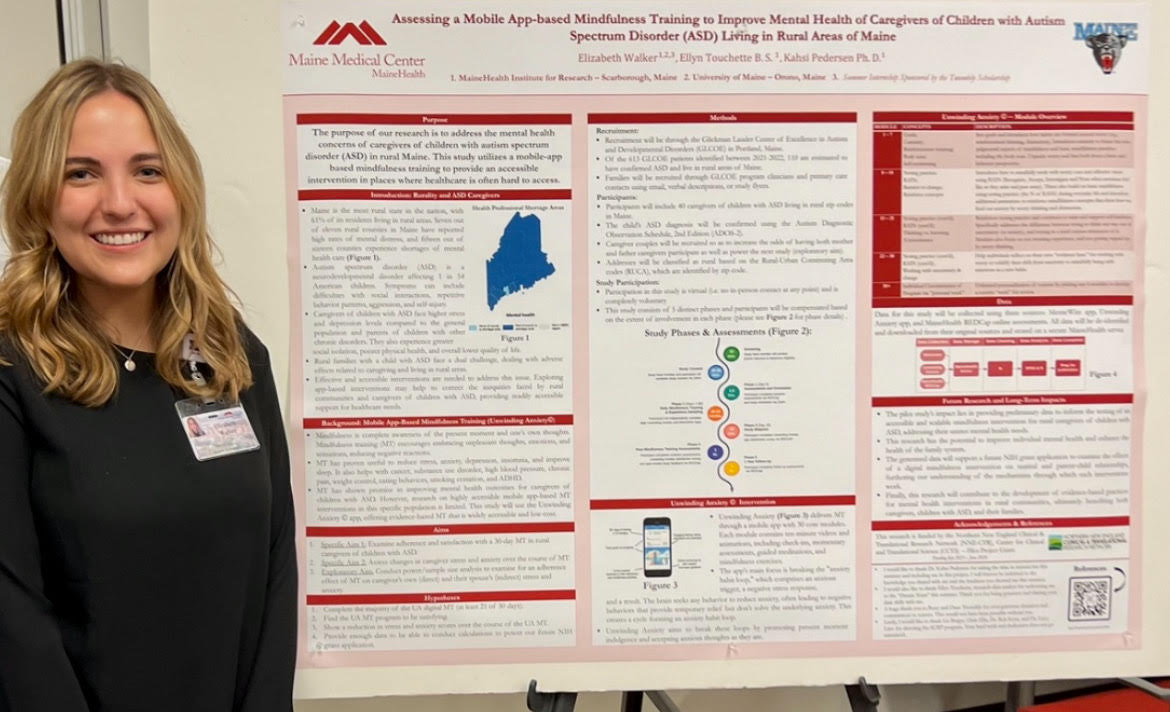 Ellie Walker poses beside her poster at the UMaine Student Symposium