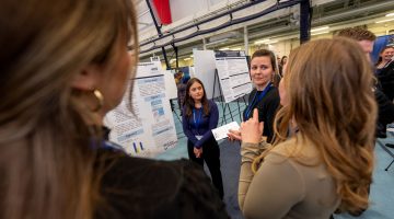 Students discuss a poster during the 2024 UMaine Student Symposium