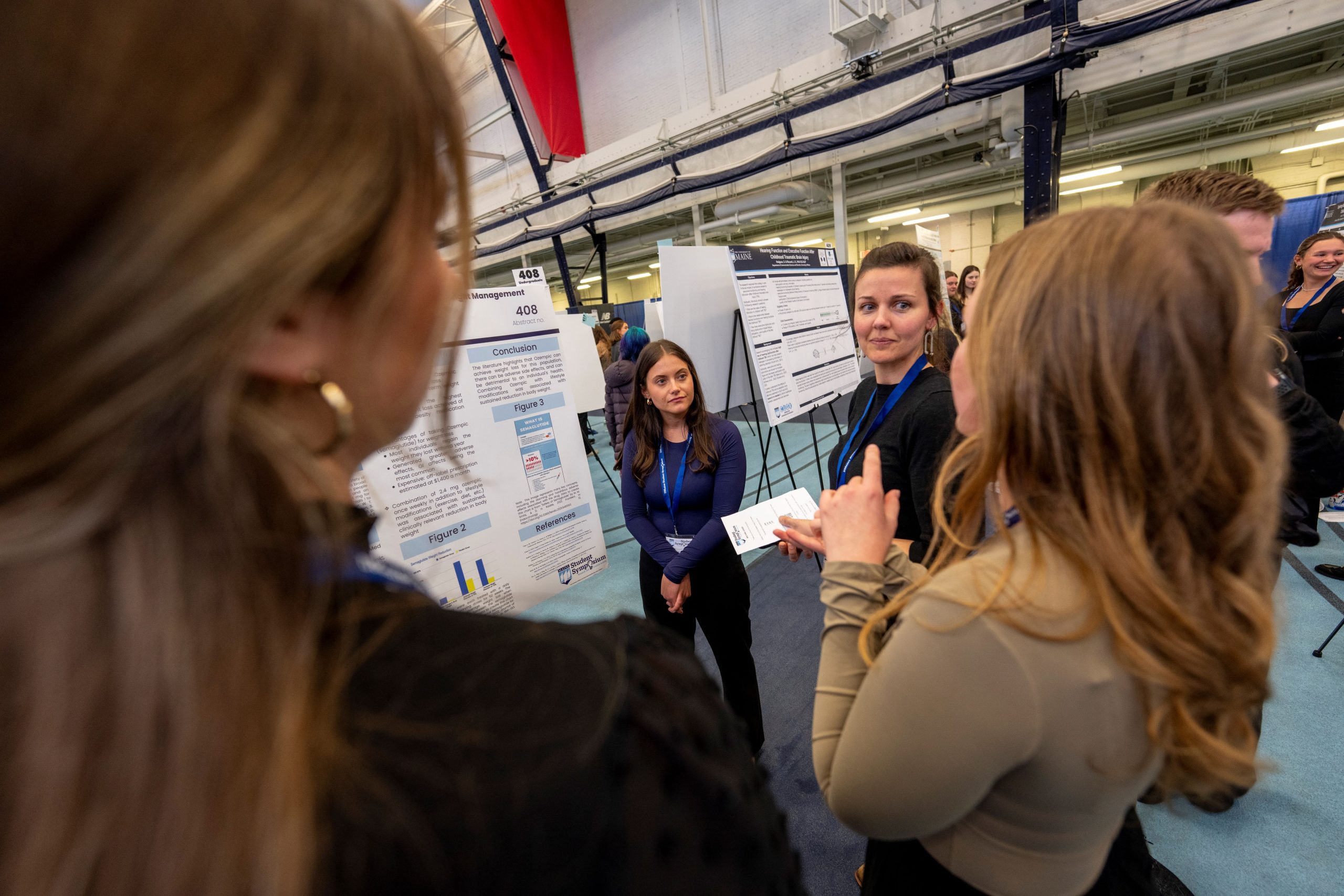 Students discuss a poster during the 2024 UMaine Student Symposium