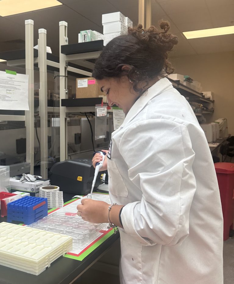 Oyku Guktug works in a lab, dispensing solution into a test tube.