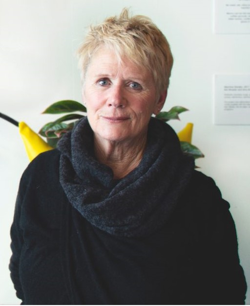 Susan Smith poses in front of an art wall in the Innovative Media Research Commercialization Center (IMRC).